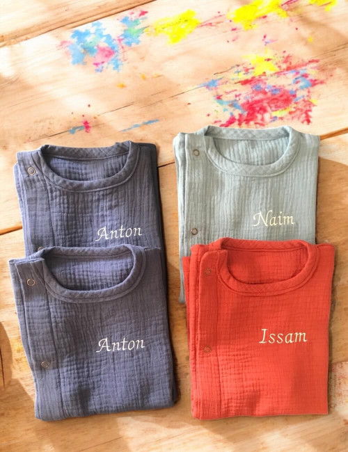 Tablier enfant sans manches en double gaze de coton bleu indigo, bleu jean, terracotta, broderie prénom pliés