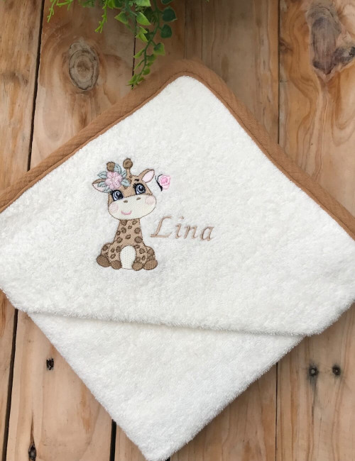 Cape de bain bébé personnalisée avec broderie prénom Lina et motif girafe, pliée pour un cadeau naissance.